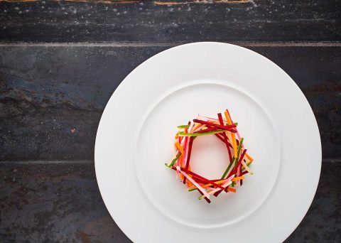 juliennes de légumes taillés dans une assiette plate en porcelaine blanche