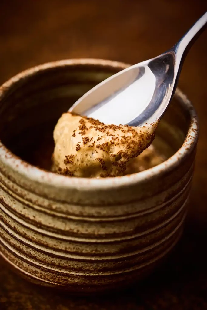 Mousse aérienne prélevée à la cuillère dans un bol en céramique – photographie culinaire studio à Lyon