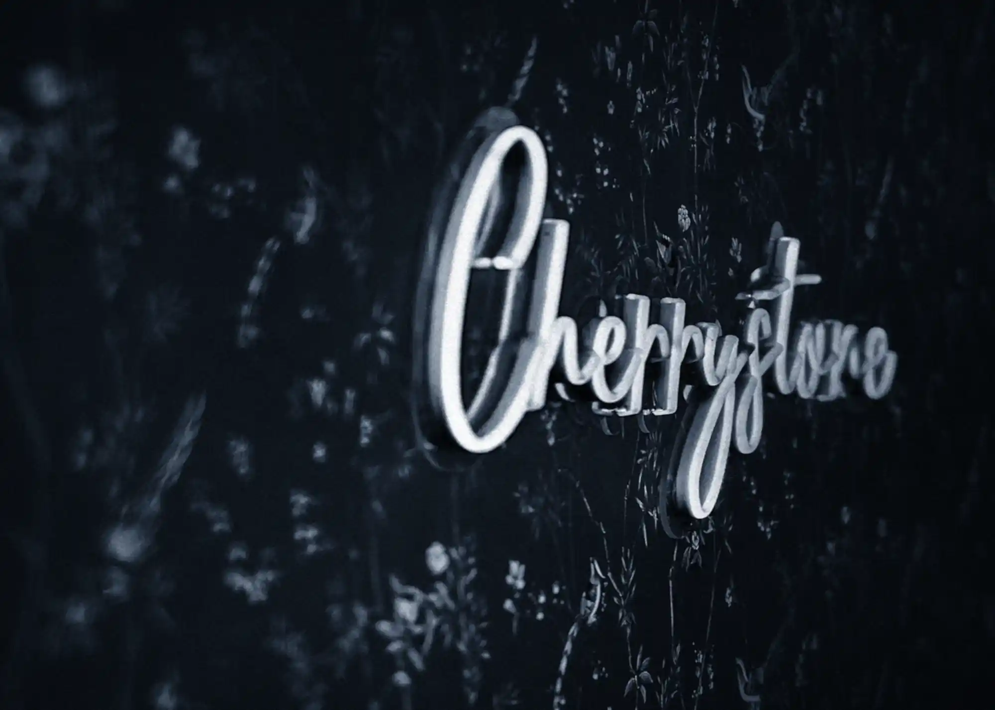 Logo en lettres lumineuses "Cherrystone" sur un mur noir fleuri dans le studio de photographie culinaire à Lyon.