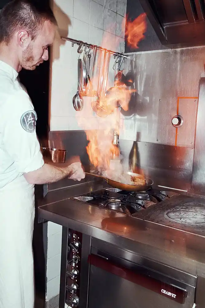 Chef réalisant un flambage en cuisine pour un accord mets et Clairette de Die Jaillance