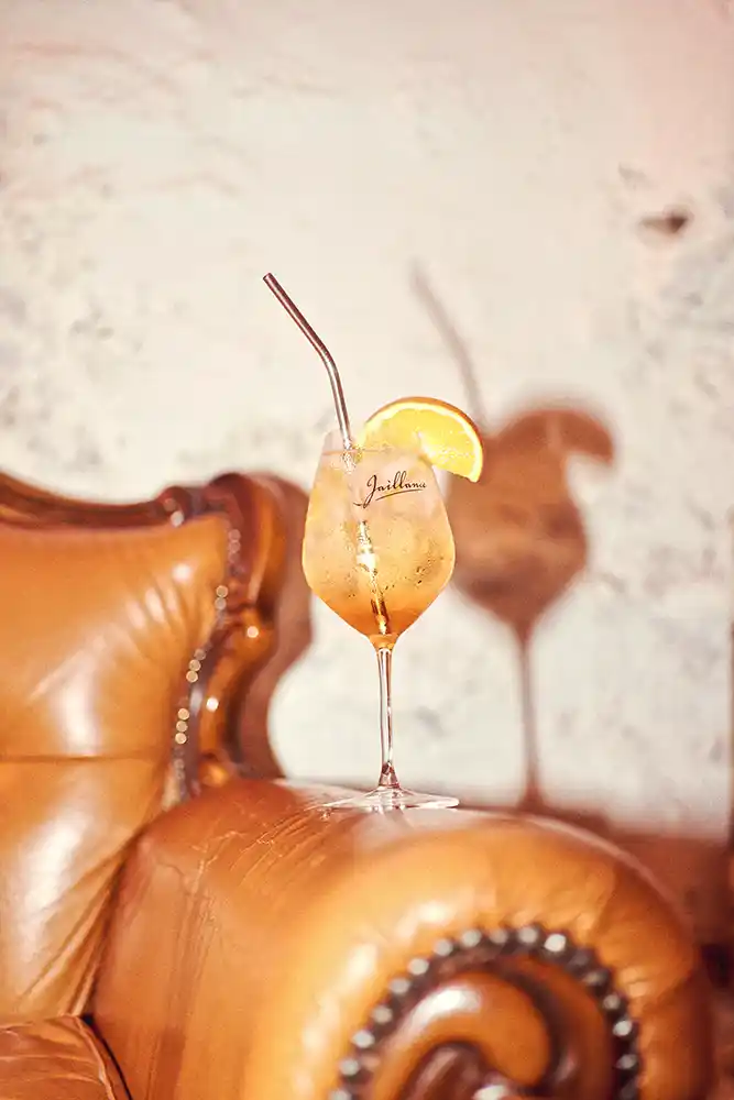 Spritz à la Clairette de Die Jaillance avec tranche d'orange sur un fauteuil en cuir