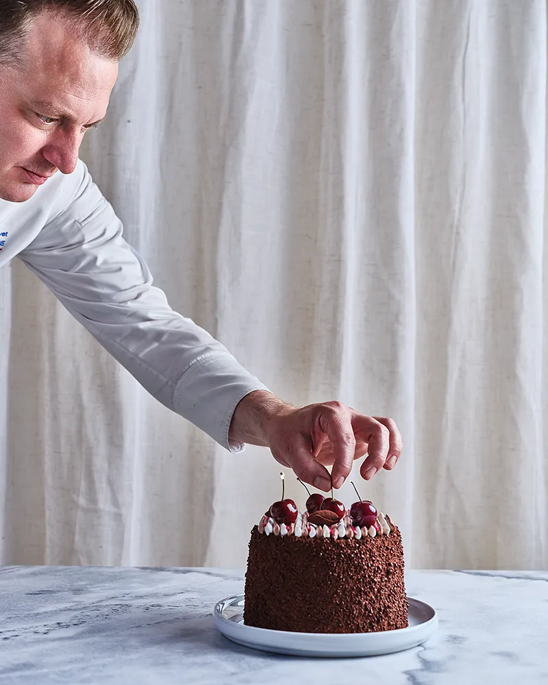 Le chef Benoît Charvet dépose des cerises sur un entremets au chocolat, geste de dressage, reportage photographe culinaire Lyon