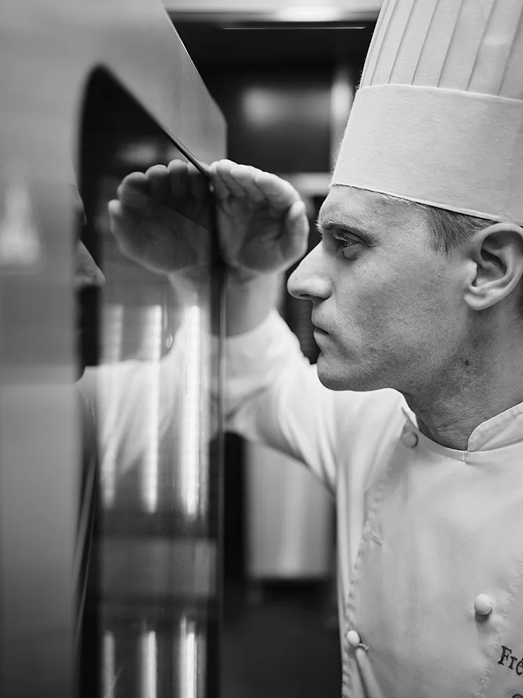 Portrait en noir et blanc d'un chef pâtissier concentré dans les cuisines du restaurant Paul Bocuse, reportage photographe culinaire Lyon