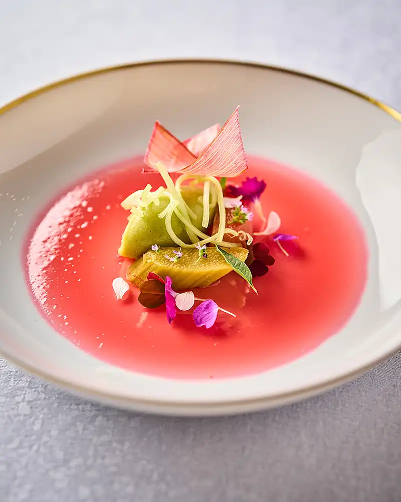 Plat gastronomique émulsion rose, légumes et fleurs comestibles dans une assiette creuse, restaurant Saisons, photographe culinaire Lyon