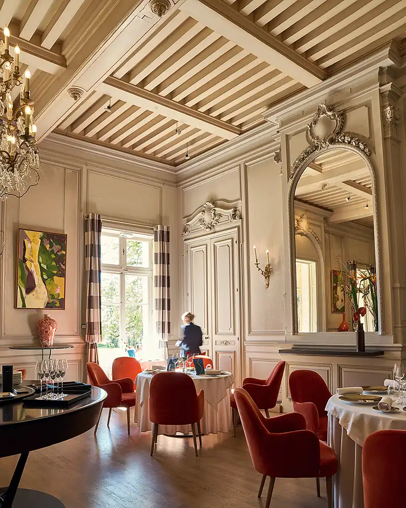 Salle du restaurant étoilé Saisons, fauteuils rouges, lustre et miroir, lumière de fenêtre, photographe culinaire Lyon